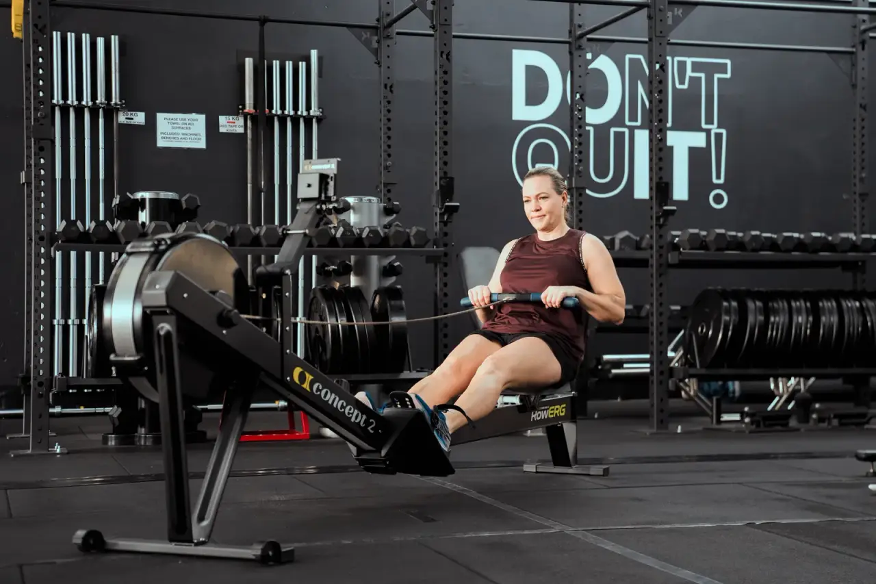 A member training on the rowing machine on the studio floor