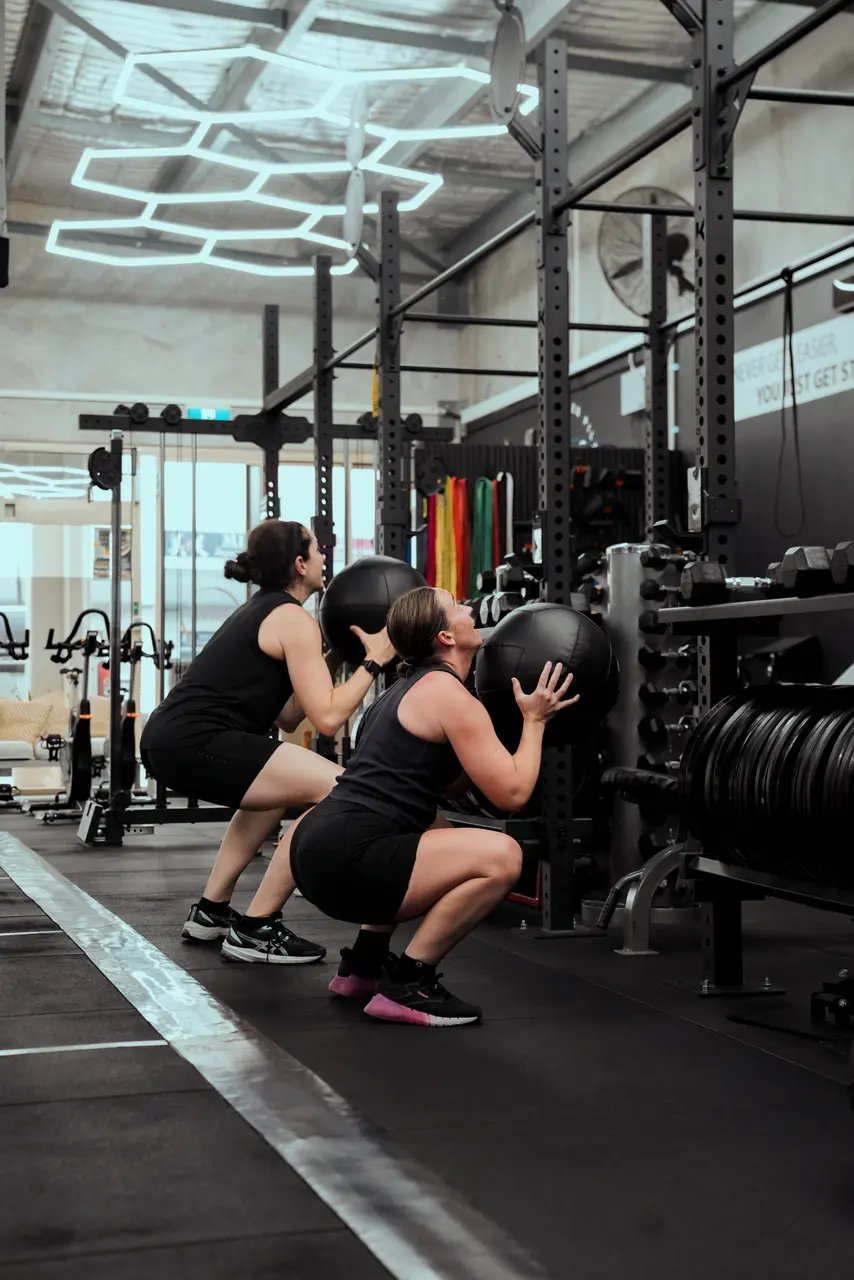 Two members training wall balls side by side