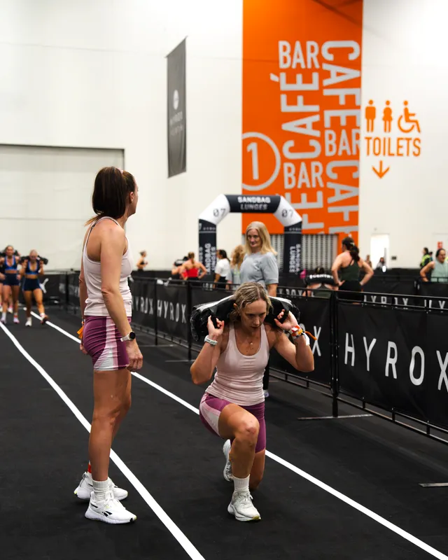 A competitor coached through sandbag lunges at a HYROX Perth event
