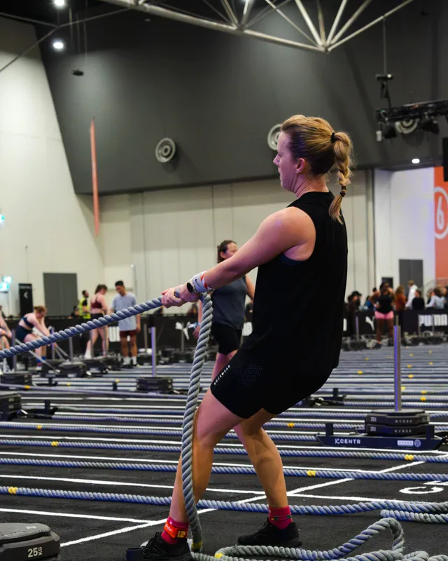 A competitor driving through a rope pull at a HYROX Perth event